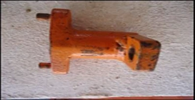Fotografia do adaptador metálico pintado de laranja, usado para transmitir o torque do torquímetro à tubulação, apoiado sobre uma superfície de concreto