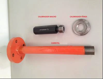 Fotografia dos três itens etiquetados lado a lado — CALIBRADOR MACHO (peça escura roscada), CALIBRADOR FÊMEA (anel metálico) e CARRETEL (tubulação laranja com flange) — apoiados sobre uma superfície branca